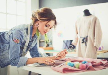 Moda tasarımcısı kadın stüdyoda tasarımları üzerinde çalışıyor.