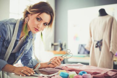 Moda tasarımcısı kadın stüdyoda tasarımları üzerinde çalışıyor.