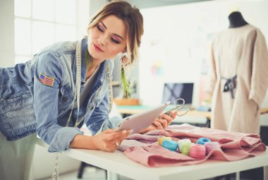 Moda tasarımcısı kadın stüdyoda tasarımları üzerinde çalışıyor.