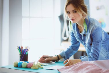 Moda tasarımcısı kadın stüdyoda tasarımları üzerinde çalışıyor.