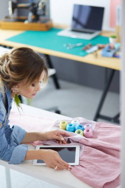 Moda tasarımcısı kadın stüdyoda tasarımları üzerinde çalışıyor.