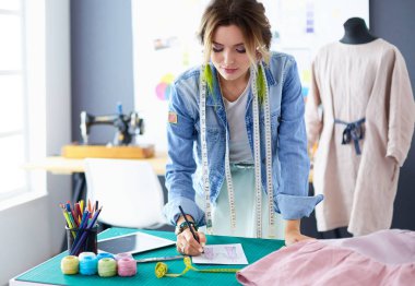 Moda tasarımcısı kadın stüdyoda tasarımları üzerinde çalışıyor.