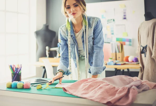 Moda tasarımcısı kadın stüdyoda tasarımları üzerinde çalışıyor.