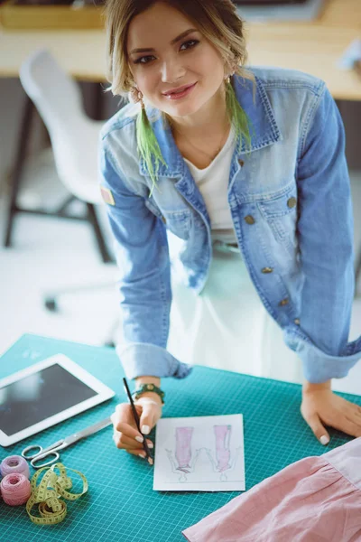 Moda tasarımcısı kadın stüdyoda tasarımları üzerinde çalışıyor.