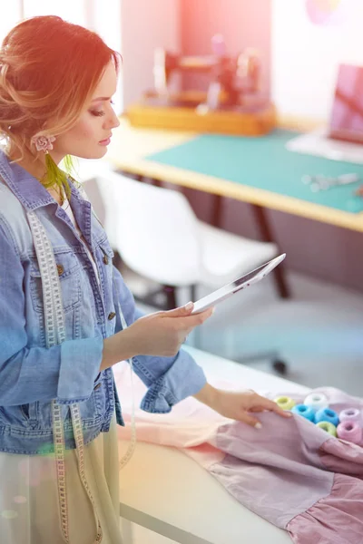 Moda tasarımcısı kadın stüdyoda tasarımları üzerinde çalışıyor.