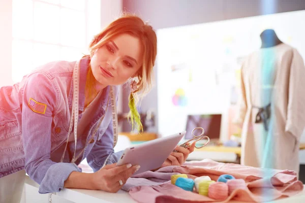 Moda tasarımcısı kadın stüdyoda tasarımları üzerinde çalışıyor.
