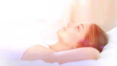 Yatakta rahat ve mutlu bir şekilde yatan güzel bir genç kadın.