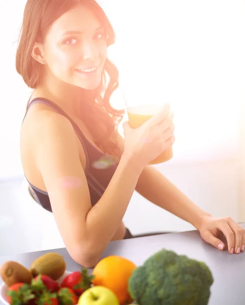 Flicka sitter i köket på skrivbord med frukt och glas med juice — Stockfoto