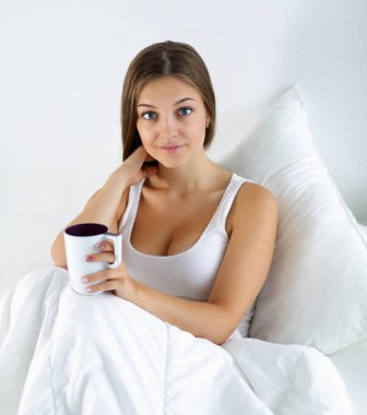 Genç ve güzel bir kadın yatakta çay keyfi