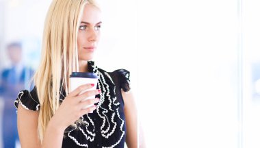 Ofiste bir fincan kahve ayakta tutan işkadını