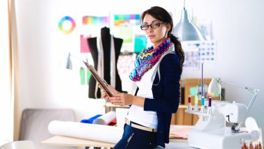 Güzel moda tasarımcısı stüdyoda duruyor.