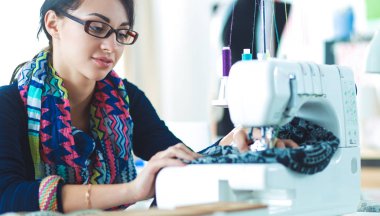 Çalışırken dikiş diken genç bir kadın.