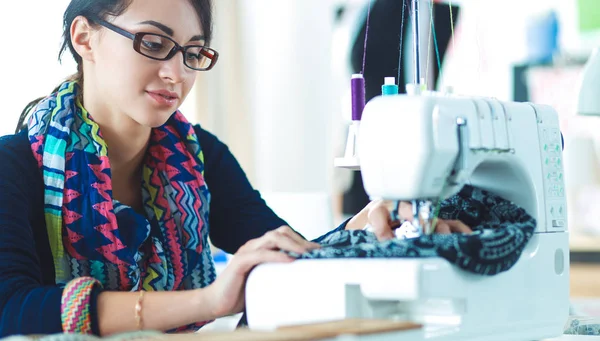 Young woman sewing while sitting at her working place — Stock Photo, Image