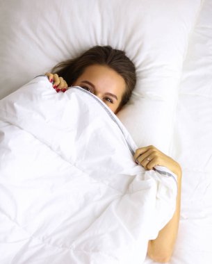 Genç ve güzel bir kadın yatakta yatıyor.