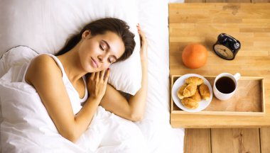 Genç ve güzel bir kadın yatakta yatıyor.