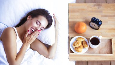 Genç ve güzel bir kadın yatakta yatıyor.