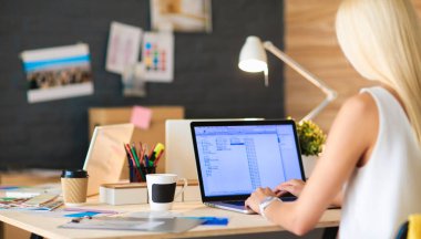 Moda tasarımcıları stüdyoda çalışıyor. Masanın üzerinde oturuyorlar.