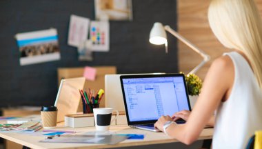 Moda tasarımcıları stüdyoda çalışıyor. Masanın üzerinde oturuyorlar.