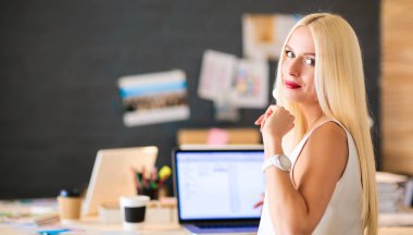 Moda tasarımcıları stüdyoda çalışıyor. Masanın üzerinde oturuyorlar.