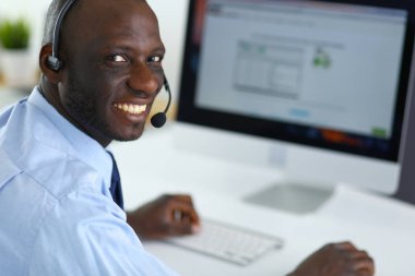 Kulaklıklı Afro-Amerikan işadamı laptopuyla çalışıyor.