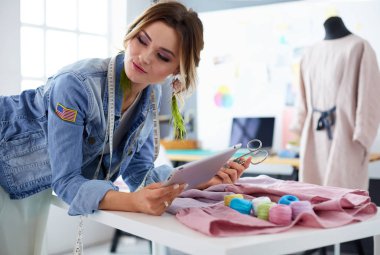 Moda tasarımcısı kadın stüdyoda tasarımları üzerinde çalışıyor.