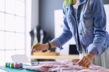 Moda tasarımcısı kadın stüdyoda tasarımları üzerinde çalışıyor.