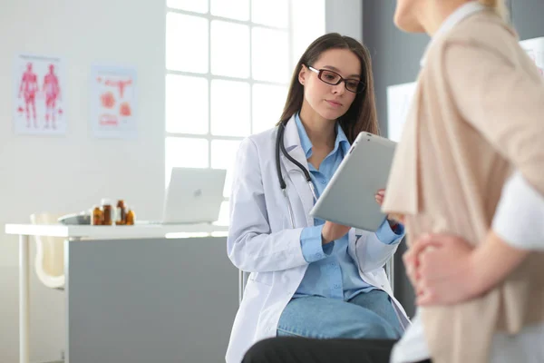 Лікар і пацієнт обговорюють щось, сидячи за столом. Медицина та концепція охорони здоров'я — стокове фото
