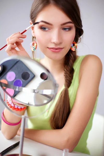 Young beautiful woman making make-up near mirror,sitting at the desk — Stock Photo, Image