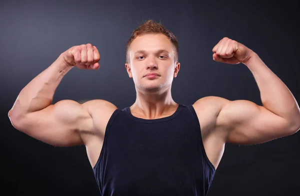 Forte e bonito jovem fisiculturista demonstrar seus músculos e bíceps — Fotografia de Stock