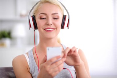 Evdeki genç ve güzel kadın kanepede oturup müzik dinliyor.