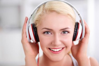 Evdeki genç ve güzel kadın kanepede oturup müzik dinliyor.