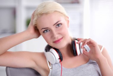 Evdeki genç ve güzel kadın kanepede oturup müzik dinliyor.