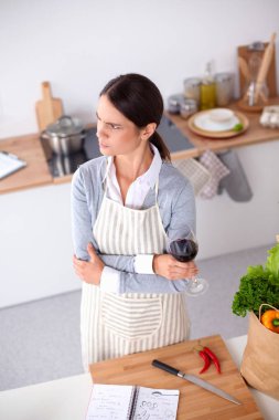 Güzel kadın mutfakta şarap içiyor.