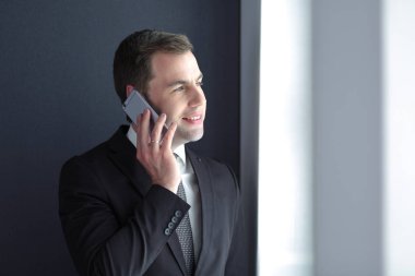 Modern ofiste cep telefonuyla konuşan yakışıklı iş adamı..