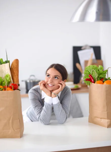 Een jonge vrouw die een boodschappentas met groenten vasthoudt. Staande in de keuken — Stockfoto