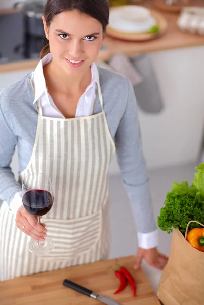 Mujer bonita bebiendo un poco de vino en casa en la cocina — Foto de Stock