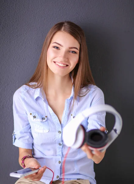 Joven chica feliz sentada en el suelo y escuchando música — Foto de Stock