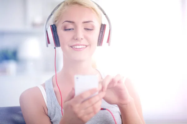 Joven hermosa mujer en casa sentada en el sofá y escuchando música — Foto de Stock