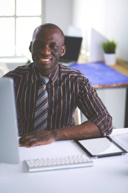 Ofiste bilgisayar ve planlarla çalışan Afrikalı Amerikalı bir mimar.