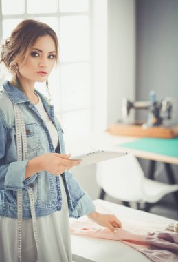 Moda tasarımcısı kadın stüdyoda tasarımları üzerinde çalışıyor.