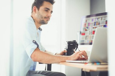 İnternette çalışırken bilgisayarın ve dizüstü bilgisayarın önünde grafik stüdyosunda oturan genç tasarımcının portresi.