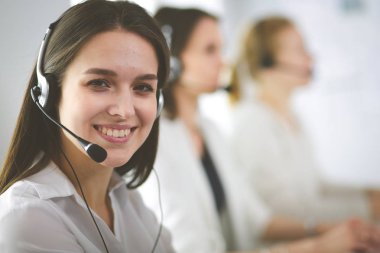 Ofisinde kulaklık ve bilgisayarla gülümseyen iş kadını ya da yardım hattı operatörü