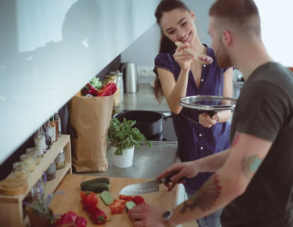 Bir çift evdeki mutfaklarında birlikte yemek pişiriyor.