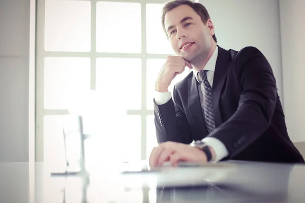 Portrait de jeune homme assis à son bureau dans le bureau. — Photo