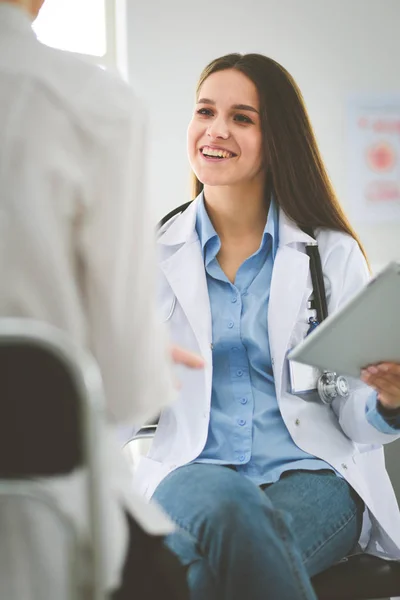 Doktorn och patienten diskuterar något när de sitter vid bordet. Medicin och hälsovård — Stockfoto