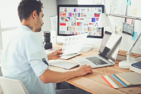 Porträt eines jungen Designers, der im Grafikstudio vor Laptop und Computer sitzt, während er online arbeitet. — Stockfoto