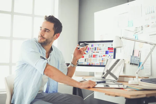 Porträt eines jungen Designers, der im Grafikstudio vor Laptop und Computer sitzt, während er online arbeitet. — Stockfoto