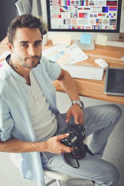 Retrato de jovem designer na frente de laptop e computador enquanto trabalhava. Assistente usando seu celular em segundo plano . — Fotografia de Stock