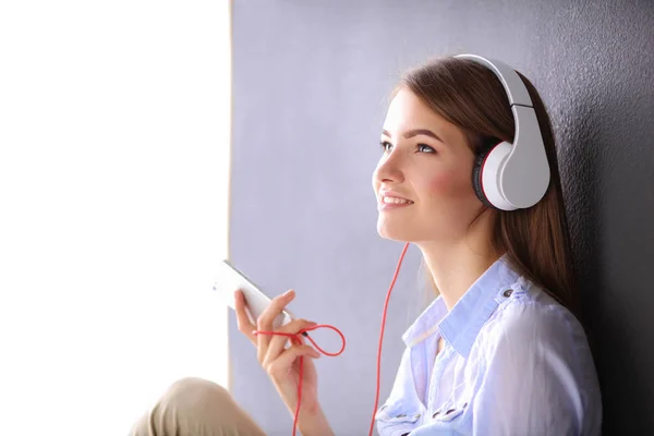 Jovem menina feliz sentado no chão e ouvir música — Fotografia de Stock