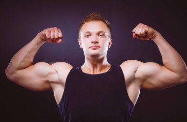 Güçlü ve yakışıklı genç vücut geliştirmeci göstermek onun kas ve pazı